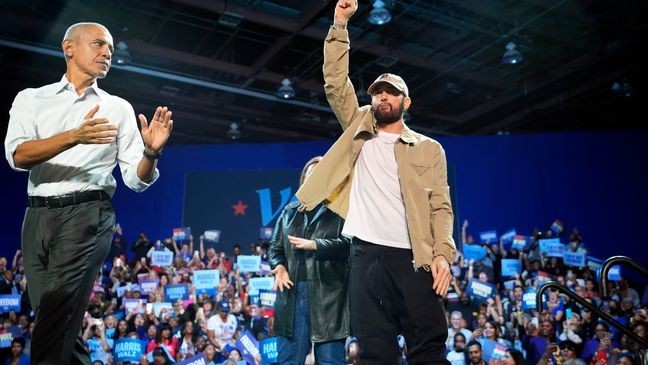 Rapper Eminem, center, greets the crowd on stage with former President Barack Obama, left, at a campaign rally supporting Democratic presidential nominee Vice President Kamala Harris, Tuesday, Oct. 22, 2024, in Detroit. (AP Photo/Paul Sancya)
